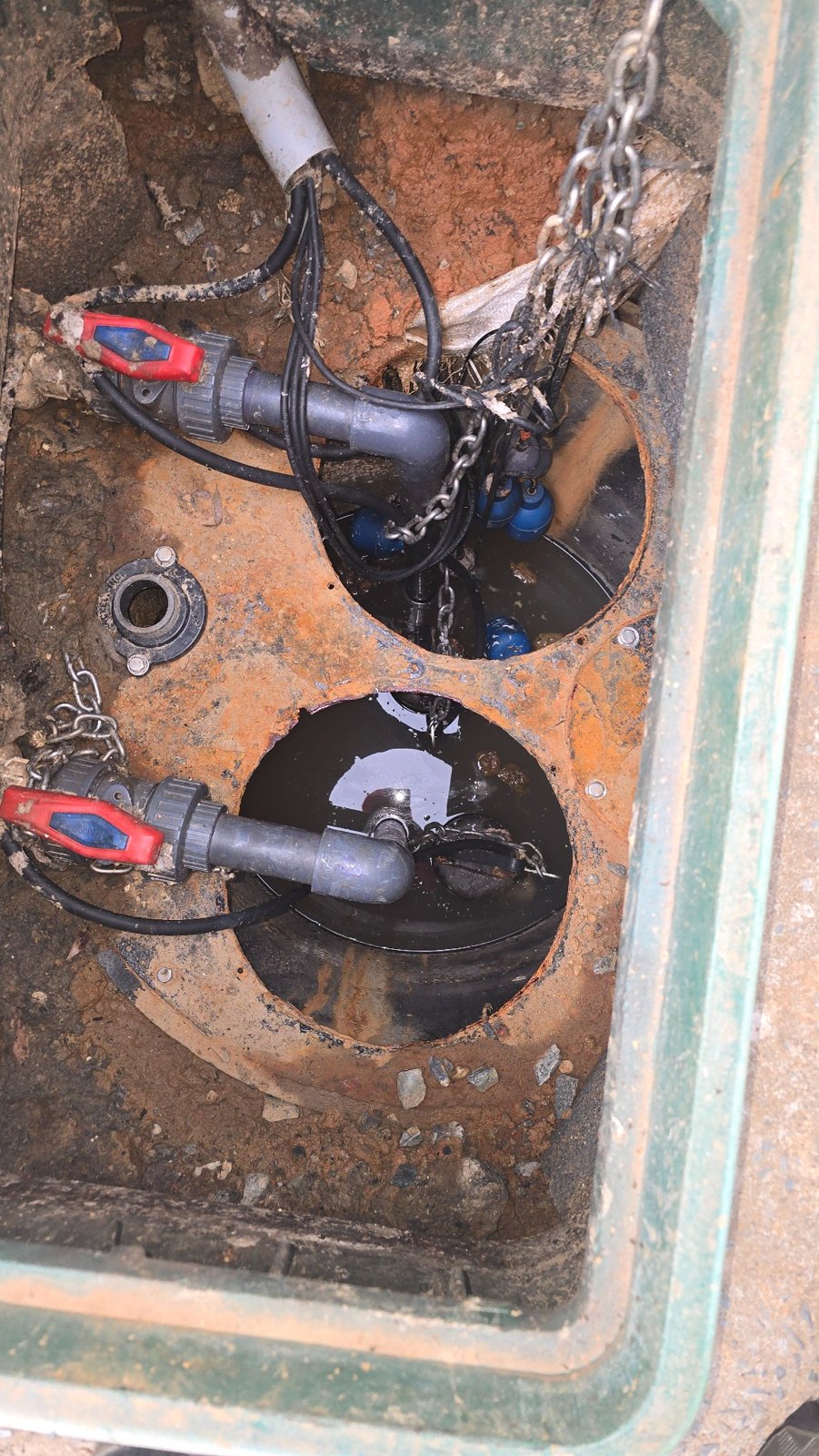Piping, valves, cables, and pump equipment inside a sewer pump basin serviced by RYN